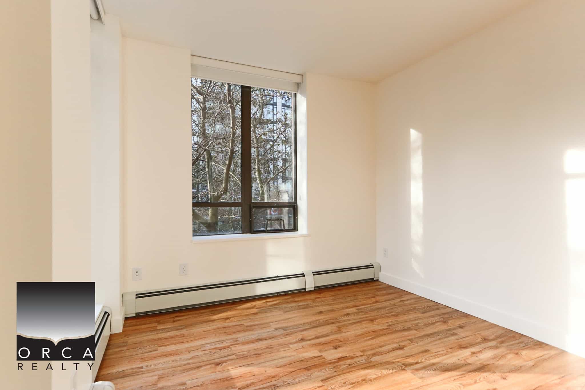 Bright, spacious living room with large window overlooking trees in North Vancouver. Perfect for comfortable living and enjoying natural light.