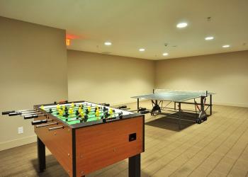 Foosball table and ping pong table in recreational game room inside a modern property.