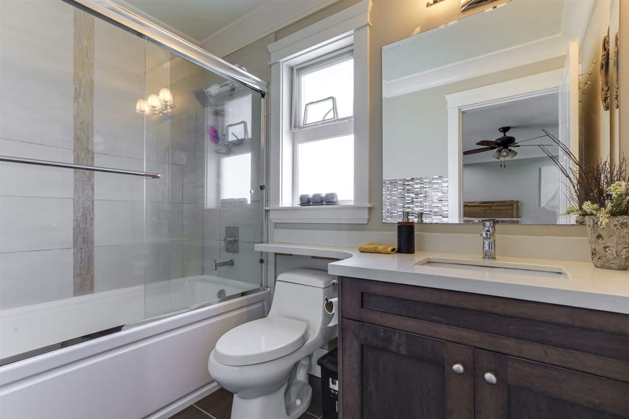 Bright modern bathroom with walk-in shower, stylish vanity with dark wood cabinet, and a large mirror, showcasing contemporary design and functional space for Vancouver area real estate.