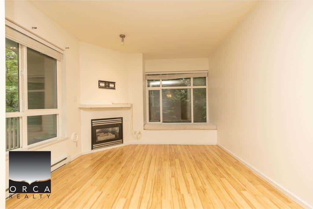 Bright living room with hardwood floors, large windows, and a cozy fireplace, ideal space for family gatherings and relaxation in a Vancouver home.