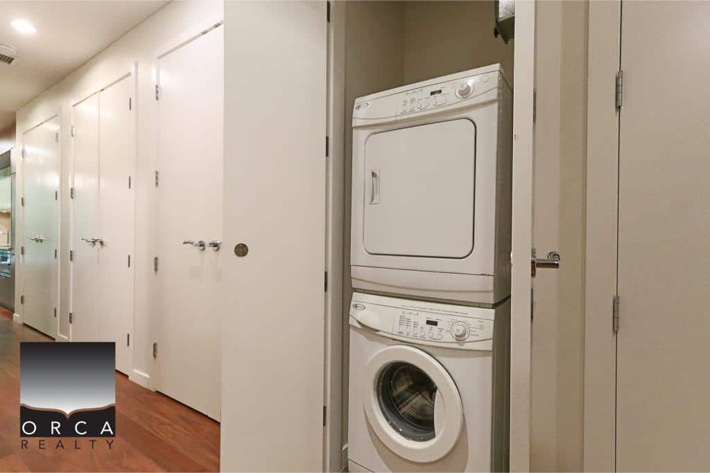 Stacked washer and dryer in a laundry area with beige walls and white cabinetry for efficient home living in Ontario.