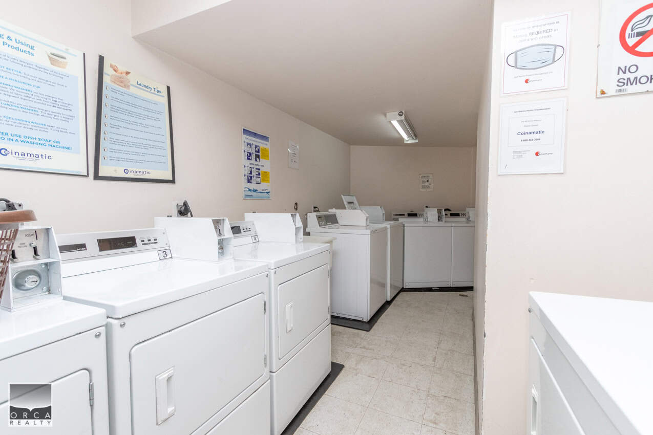 Washer and dryer laundry area at Orca Realty Inc., Vancouver real estate agency, featuring top laundry machines and essential drying facilities.