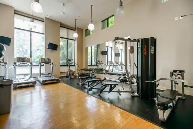 Spacious gym with cardio equipment, weight machines, and workout benches at Orca Realty Inc. offering premium real estate services in the Vancouver area.