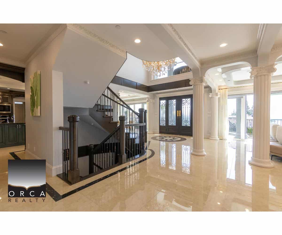 Elegant luxury home interior with grand entrance, marble flooring, decorative columns, and ornate ceiling details, showcasing premium real estate in Vancouver offered by Orca Realty Inc.