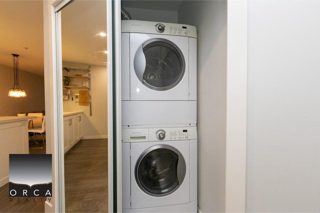 Stacked front-load washer and dryer in a laundry closet with sliding door, modern appliance setup, inside a well-lit home, ideal for real estate listings and showcasing property features.