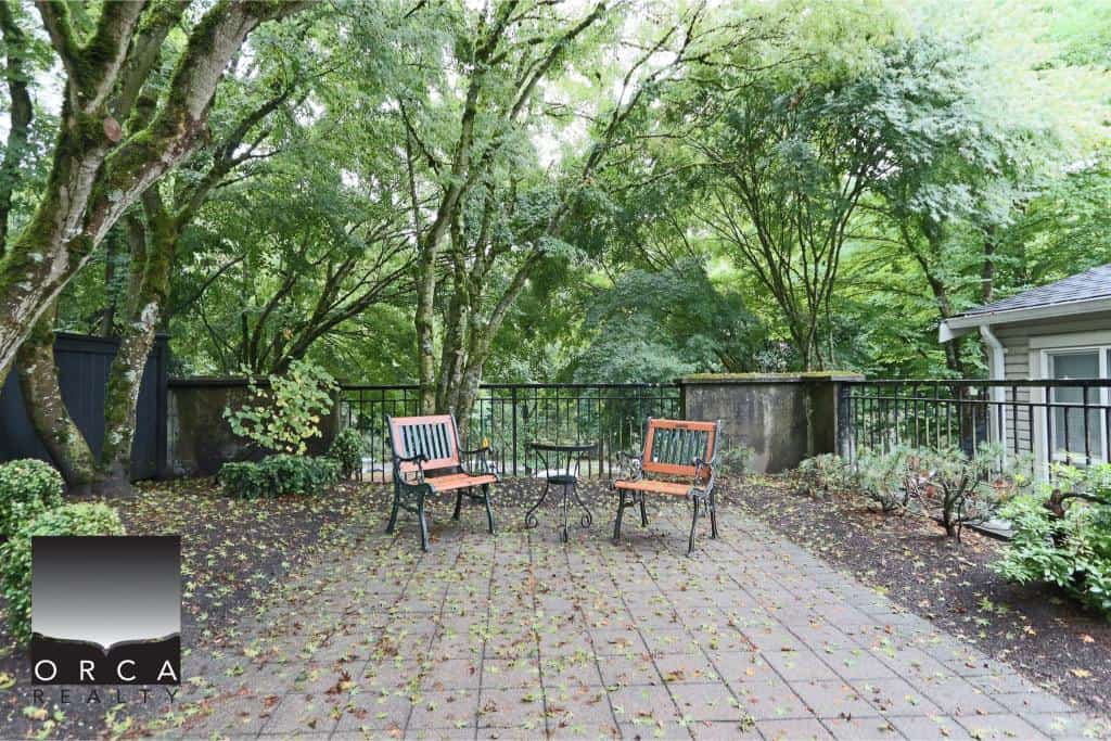 Serene outdoor patio with lush green trees, comfortable seating, and tranquil atmosphere, perfect for relaxation and outdoor living in a prime Vancouver real estate location.
