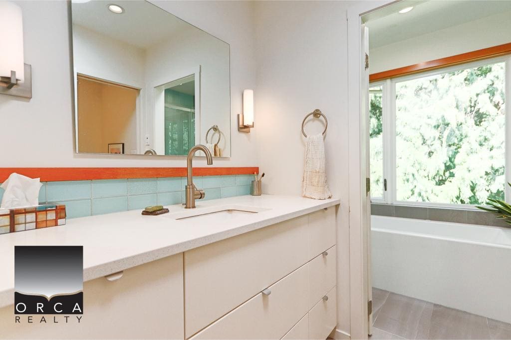 Bright bathroom with modern vanity, large mirror, and relaxing soaking tub surrounded by lush greenery, perfect for home relaxation and comfort.