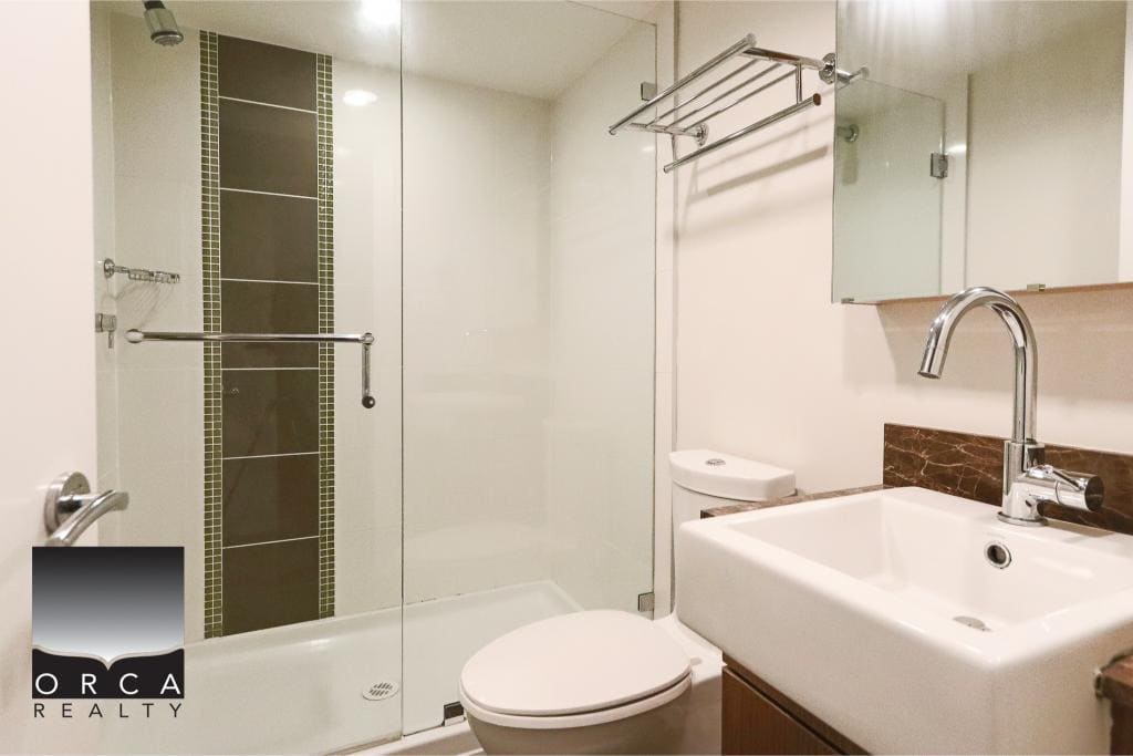 Modern bathroom with glass shower enclosure, white toilet, and contemporary fixtures, perfect for Vancouver-area homes. Expert real estate services by Orca Realty Inc. in British Columbia.