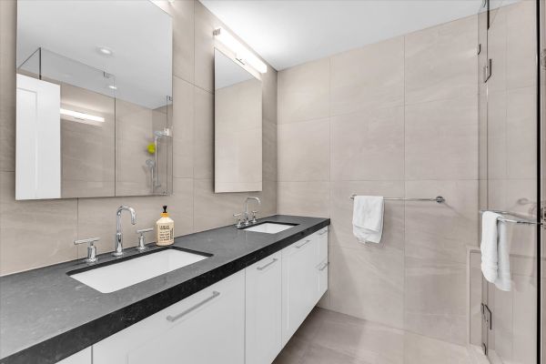 Bathroom with dual sinks, large mirror, and contemporary fixtures in a stylish, neutral-toned space.