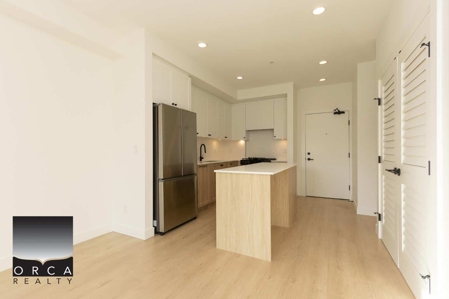Stunning modern kitchen with white cabinetry, stainless steel appliances, and an island, perfect for coastal living and real estate investment in British Columbia.