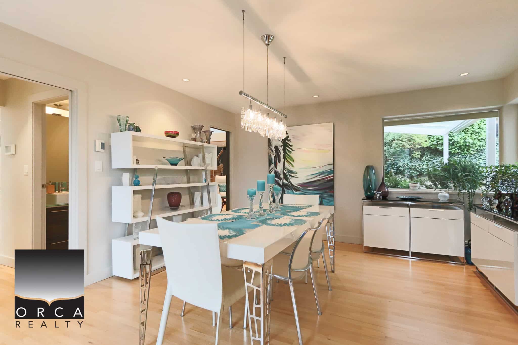 Contemporary dining room in a modern Vancouver home featuring elegant white furniture, artistic decor, and abundant natural light for a luxurious lifestyle.