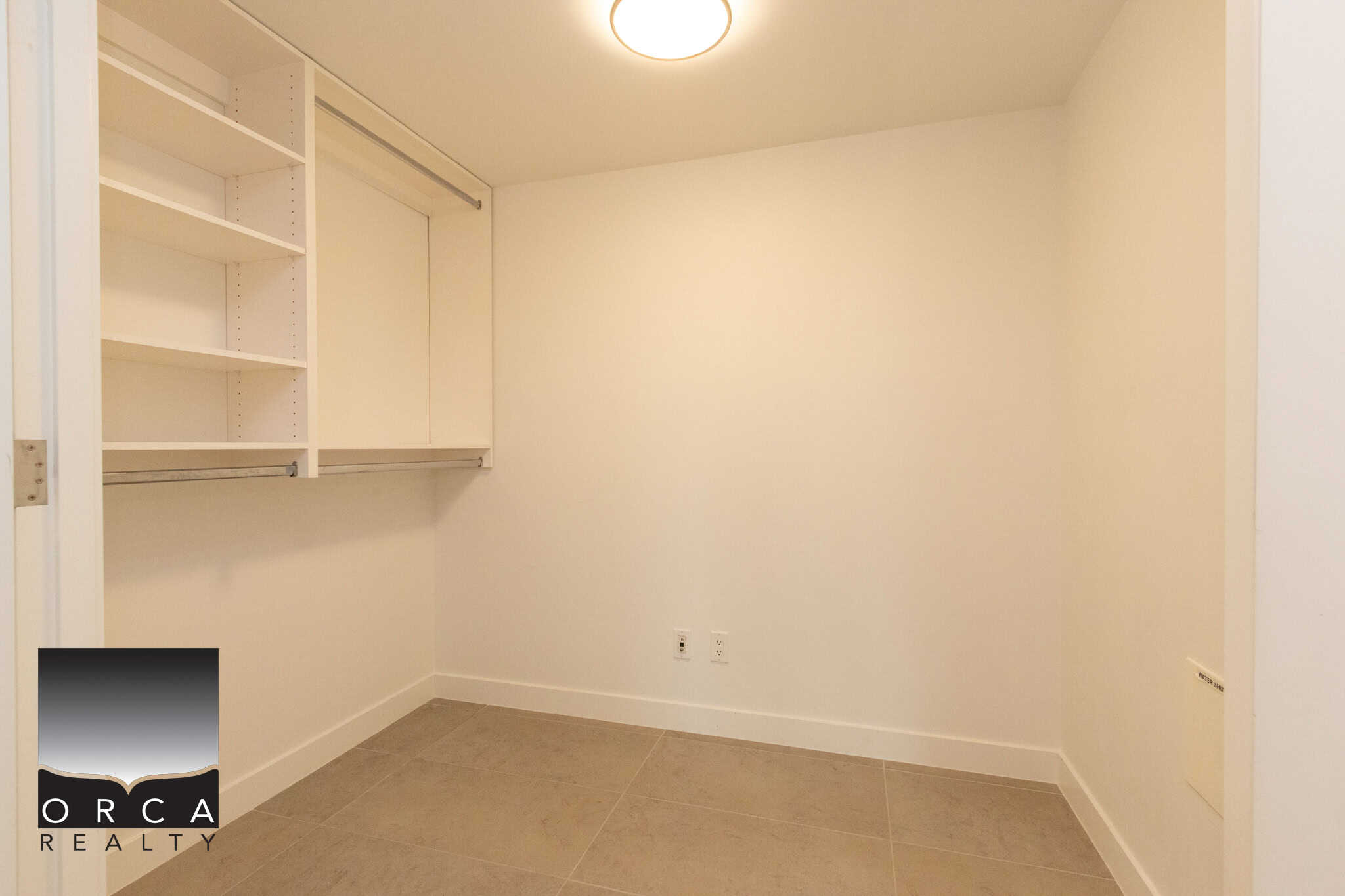 Bright, empty walk-in closet with white shelving and beige tiled flooring, ideal for organizing your wardrobe in Vancouver. Perfect space for storage and dressing.