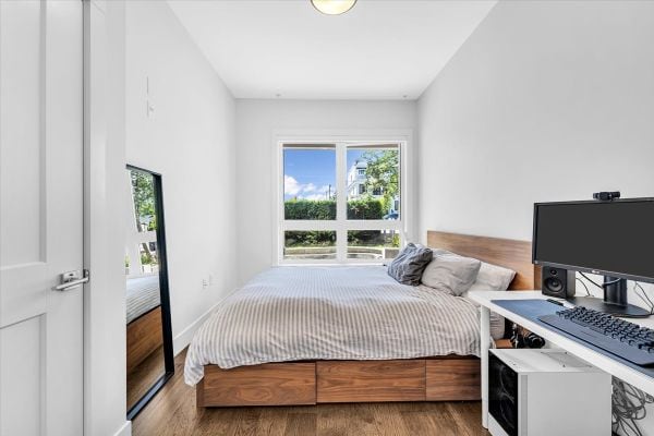 Bright Vancouver bedroom featuring a large window, minimalist decor, and a cozy bed with neutral linens. Perfect for real estate listings showcasing downtown Vancouver properties.