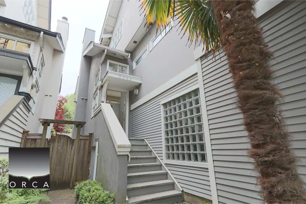 Modern multi-story condo building photographed from the front featuring exterior staircase, glass block window, and palm tree, representing Vancouver real estate options in the Greater Vancouver area.
