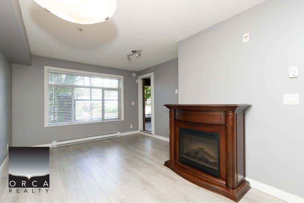 Bright living room with large window, modern design, and a cozy electric fireplace, ideal for Vancouver real estate buyers seeking stylish, comfortable homes.