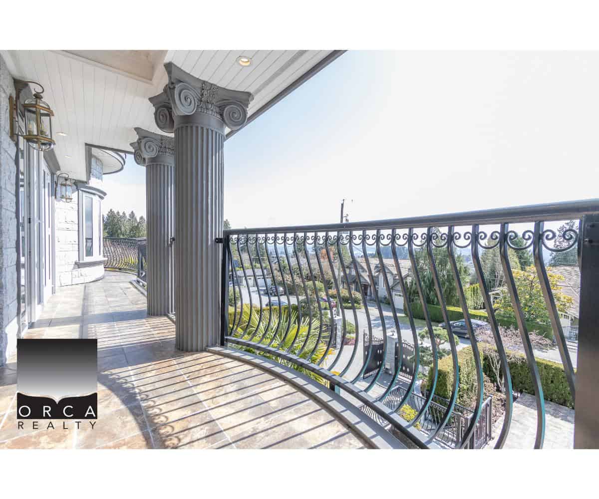 Balcony with decorative wrought iron railing and classic columns in front of a townhouse, showcasing luxury outdoor living space and property features in Vancouver, BC.