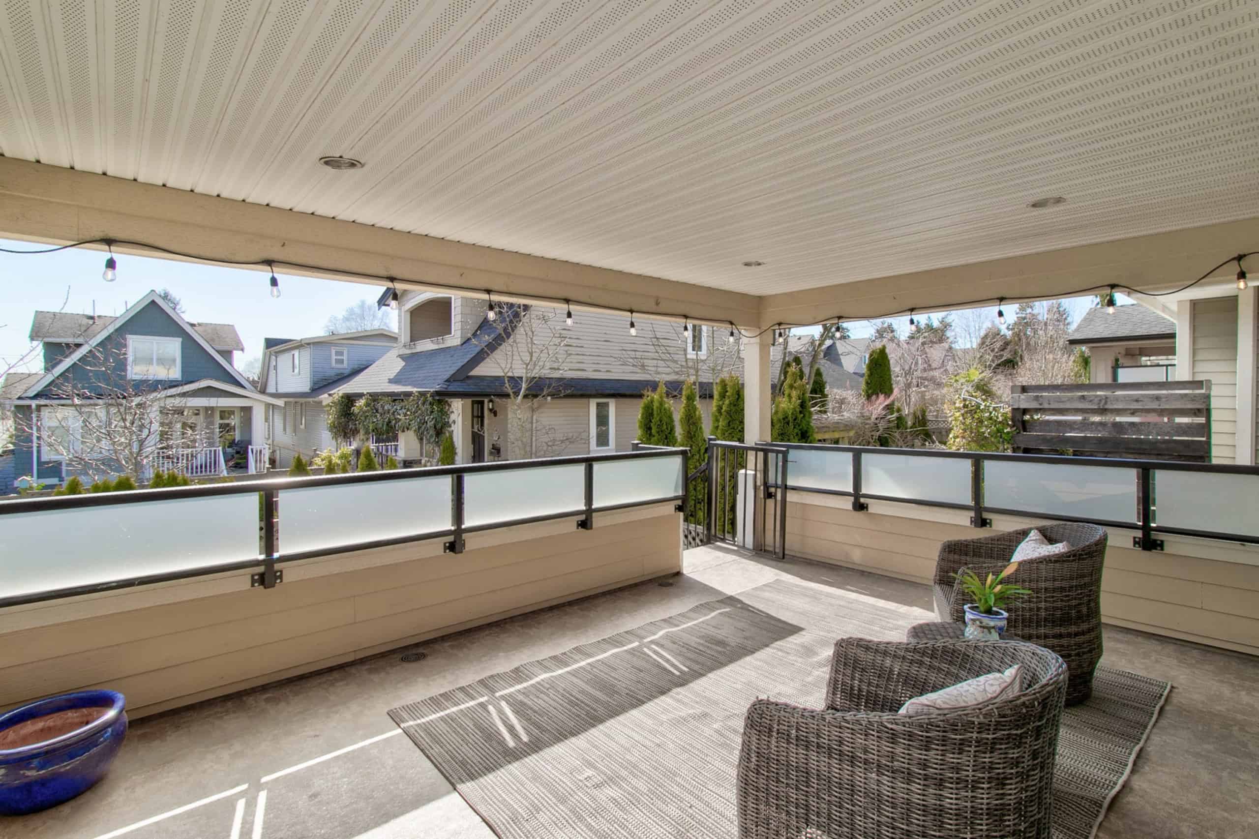 Spacious covered balcony with outdoor seating, overlooking a charming residential neighborhood in Vancouver, ideal for relaxing or entertaining clients in a professional real estate setting.