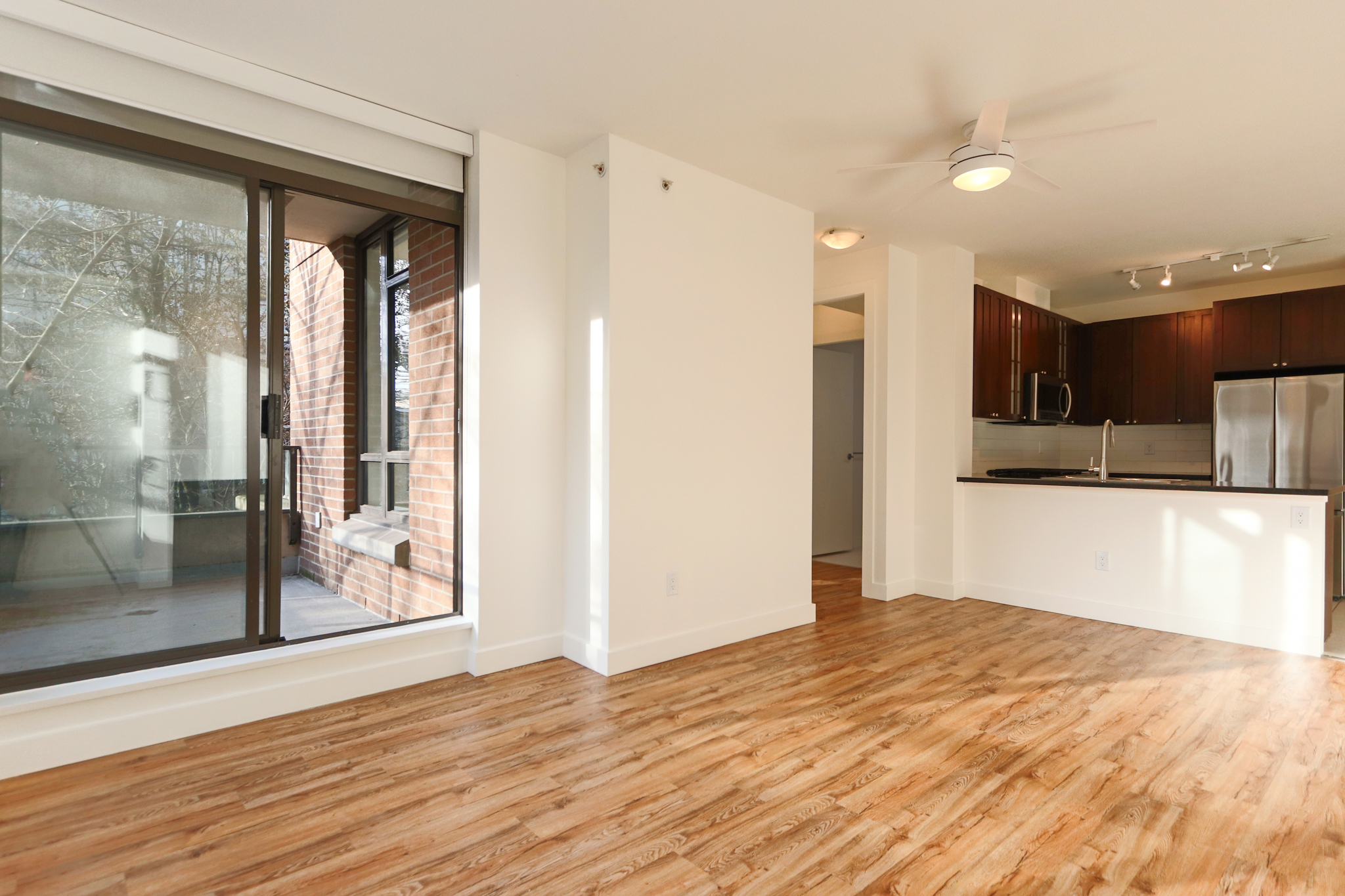 Bright and spacious North Vancouver condo interior with hardwood floors, large sliding glass door, and open kitchen layout. Perfect for modern living.