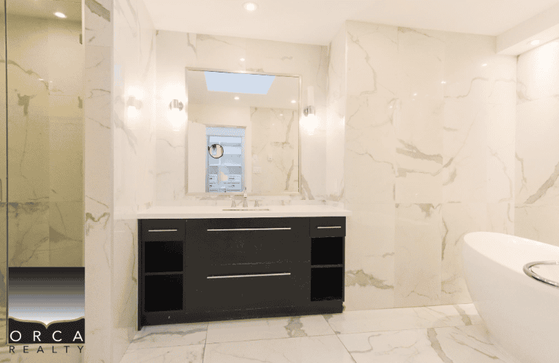 1. Modern bathroom with sleek marble walls and stylish vanity, showcasing luxurious real estate features by Orca Realty Inc.