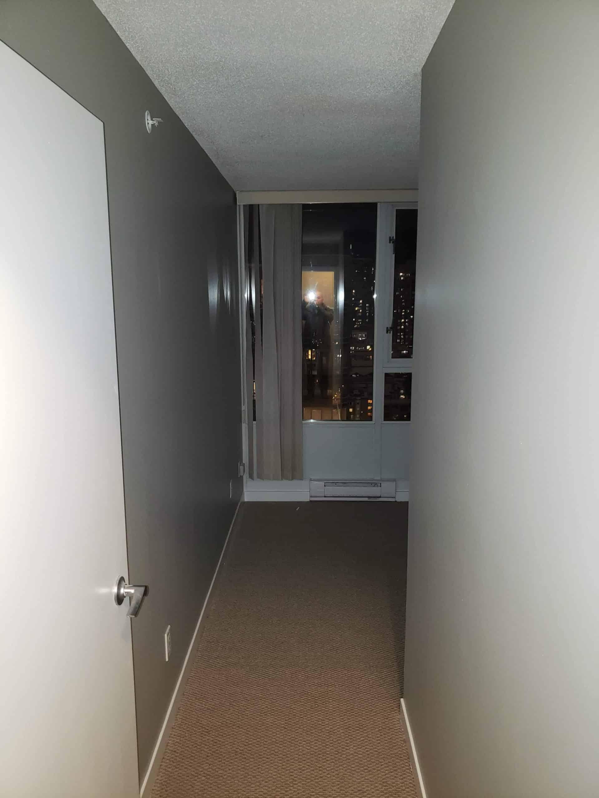 Modern apartment interior with a view of city skyline through large windows, showcasing condo living with spacious rooms, sleek design, and city lights at night - Orca Realty Inc.