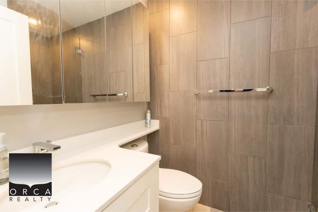 Modern bathroom with beige tile walls, white vanity, and sleek fixtures, perfect for upscale Vancouver real estate listings.