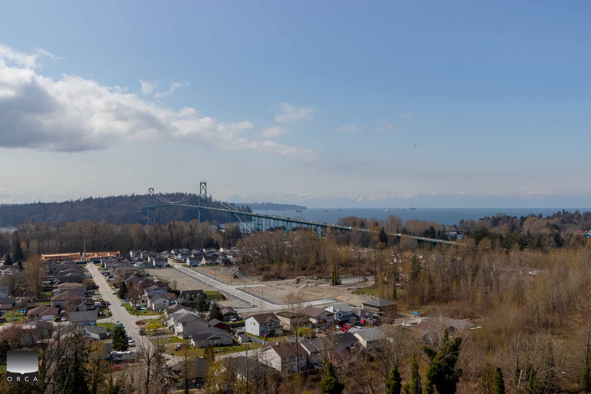 Aerial view of a coastal residential neighborhood with a bridge, ocean in the background, and lush trees, showcasing versatile properties and scenic Vancouver Island landscapes, ideal for real estate buyers.