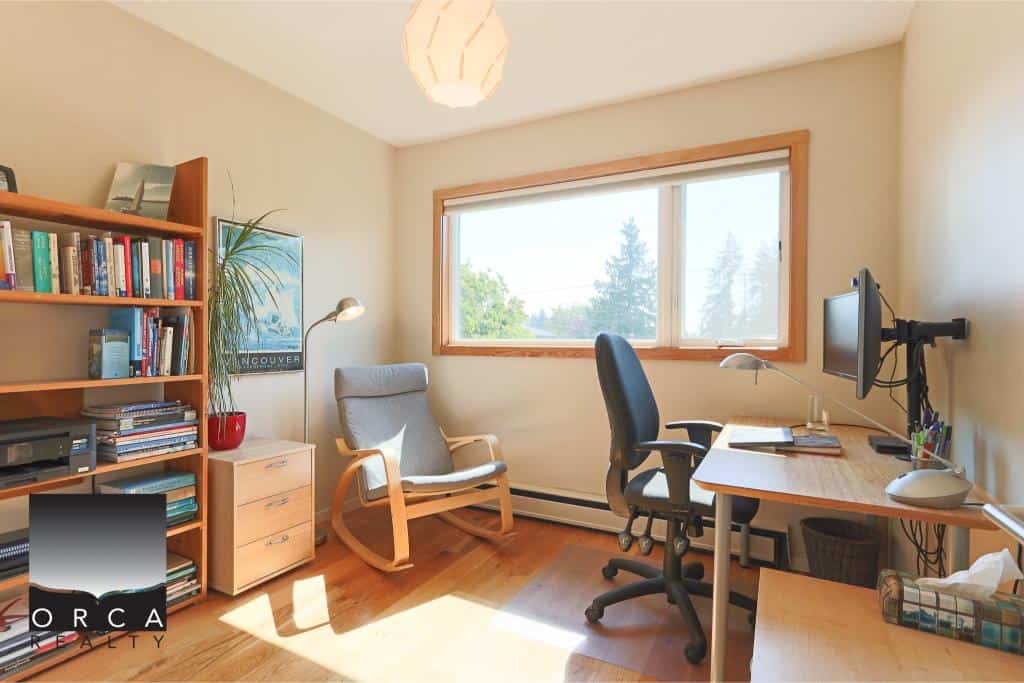 Cozy home office space with natural light, wooden desk, ergonomic chair, bookshelf, and large window, perfect for remote work or study, located in Vancouver.