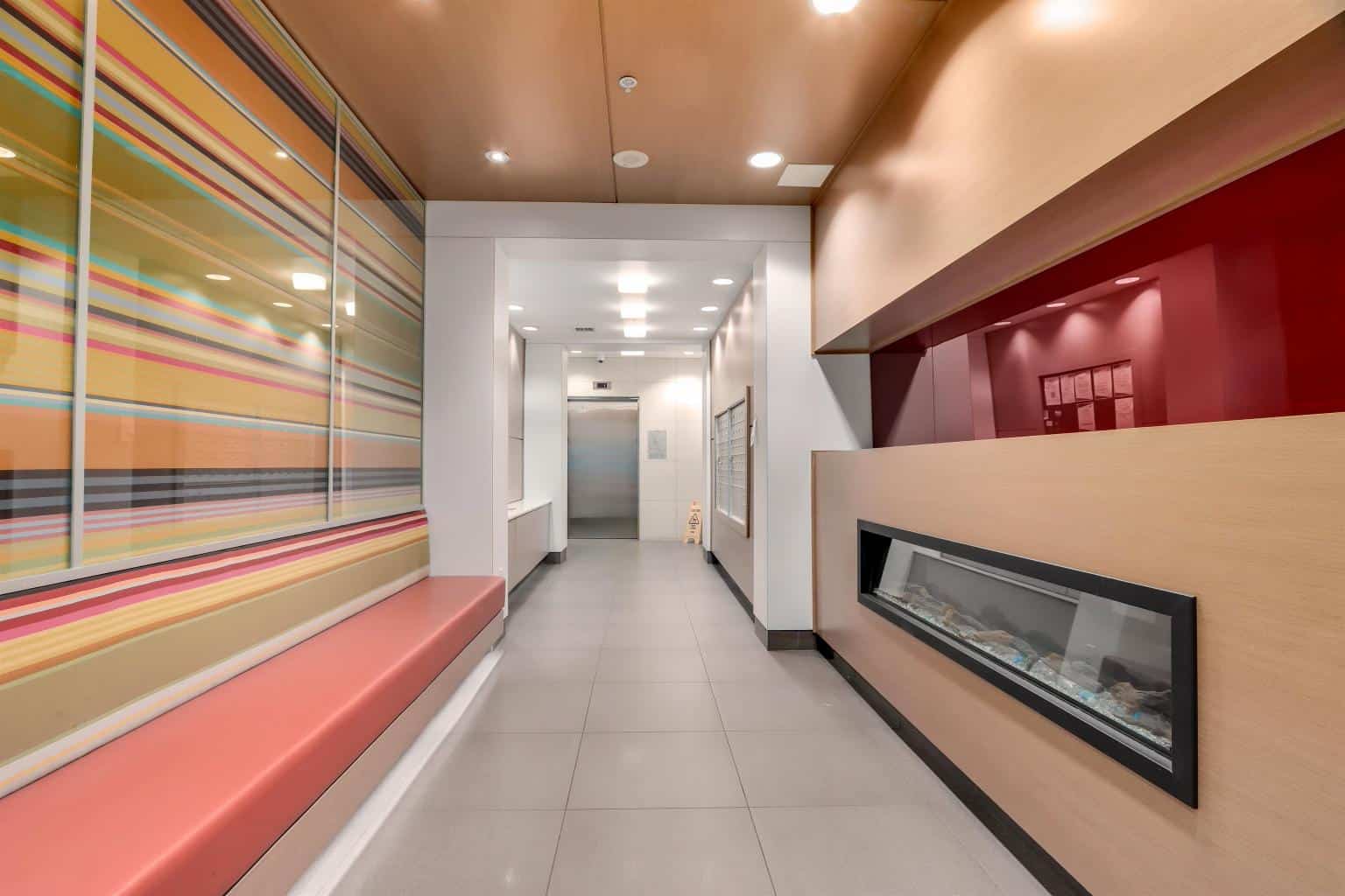 Contemporary hotel lobby with vibrant striped wall art, cozy seating area, and modern fireplace features, ideal for relaxing stays and comfortable guest experiences.