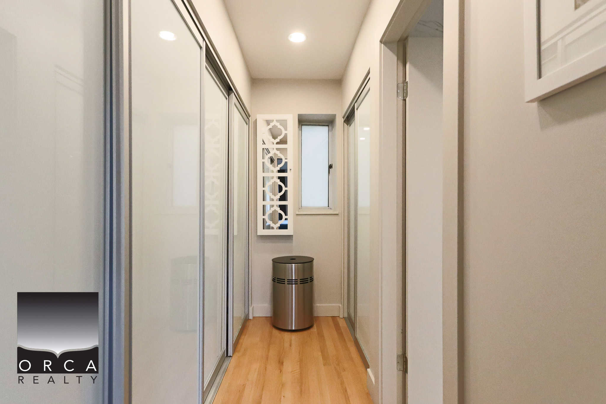 Modern interior hallway with built-in closets and hardwood flooring, showcasing contemporary home design.