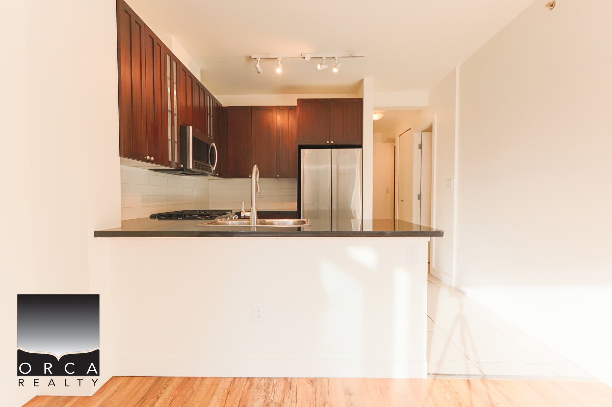 Modern kitchen in North Vancouver featuring stainless steel refrigerator, microwave, and sleek dark wood cabinets. Bright, open-concept design perfect for contemporary living.