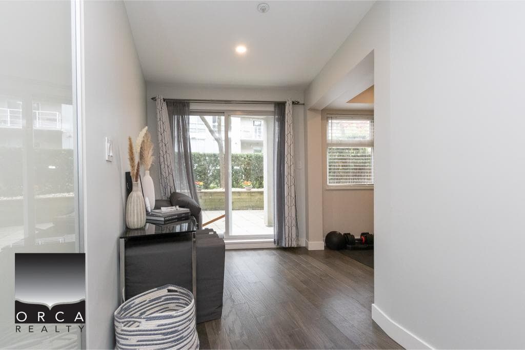 Bright modern living room with sliding glass doors leading to a balcony, featuring hardwood floors, stylish decor, and natural light, ideal for homebuyers seeking Vancouver real estate.