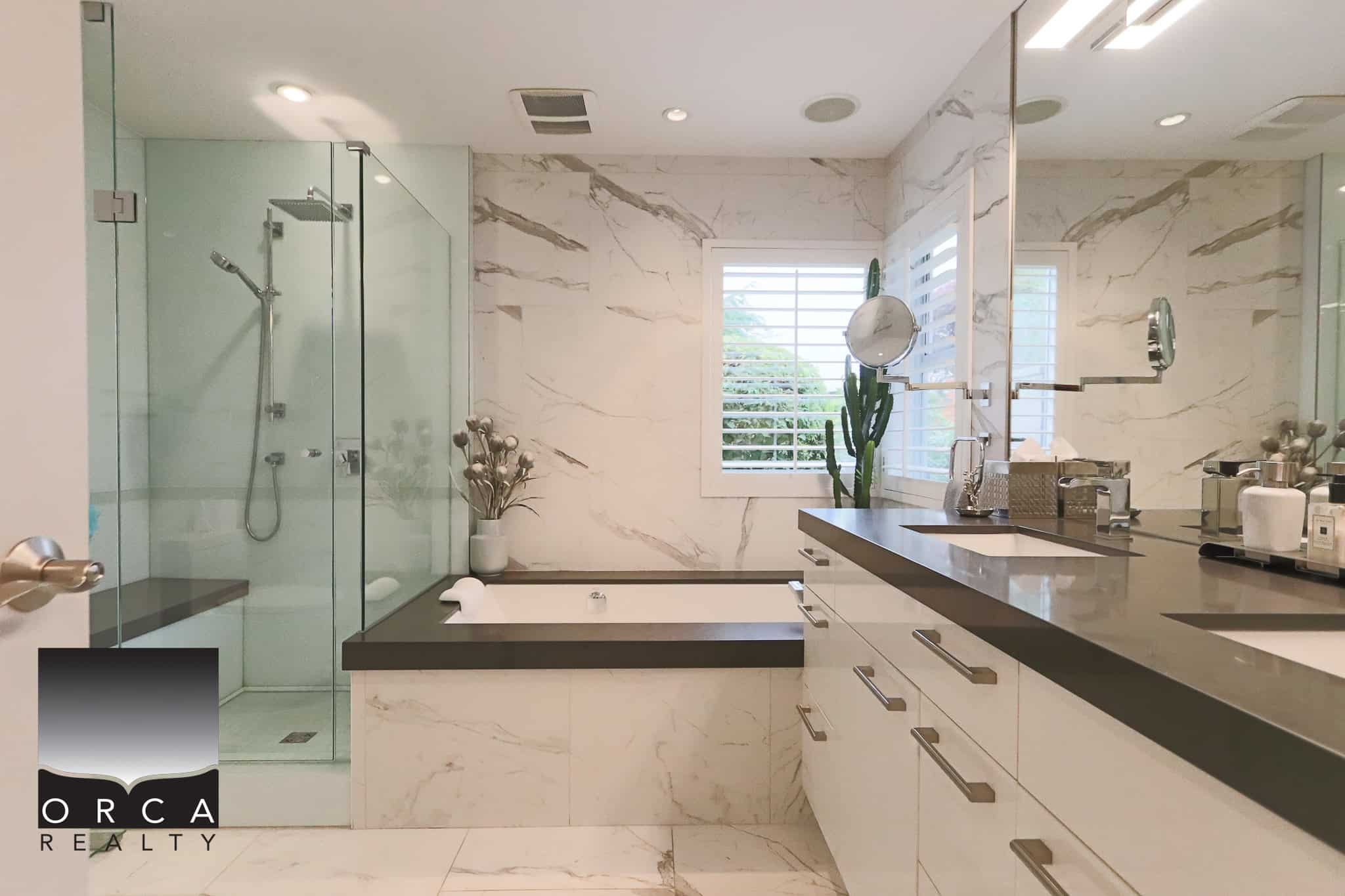 Luxurious modern bathroom featuring a walk-in shower and soaking tub with marble accents, large window with plantation shutters, and elegant vanity with pool of natural light, perfect for upscale residential real estate.