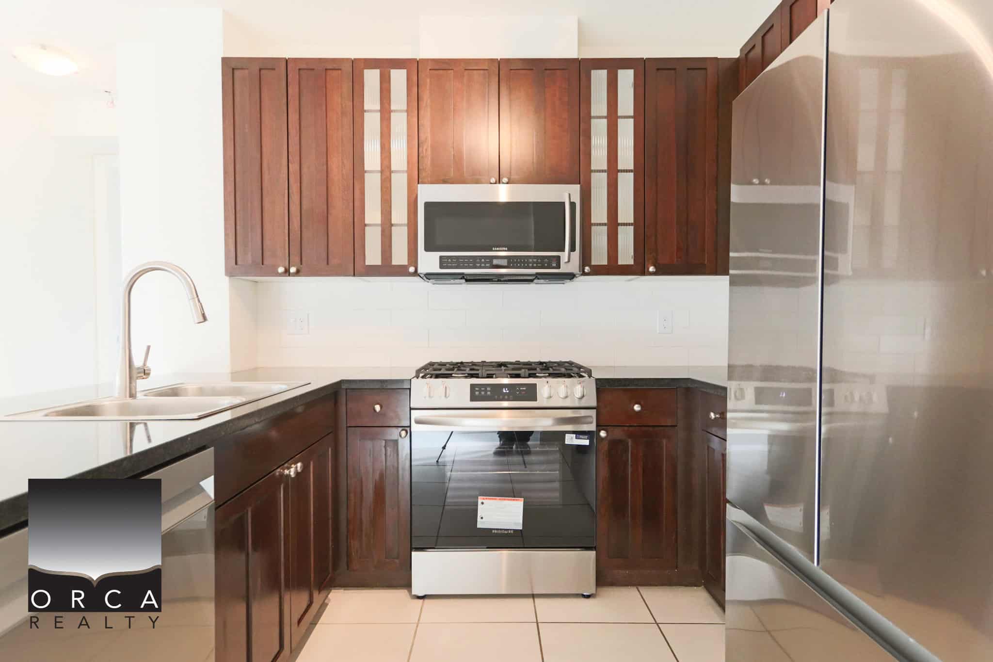 Bright, contemporary kitchen featuring stainless steel stove, microwave, and refrigerator in North Vancouver home. Perfect for cooking enthusiasts and modern living.