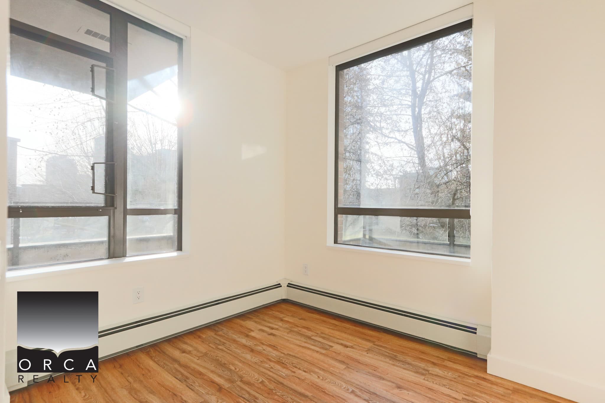 Bright North Vancouver room with large windows and natural sunlight, ideal for a cozy living space or home office. Features hardwood flooring and a clean, minimalist design.
