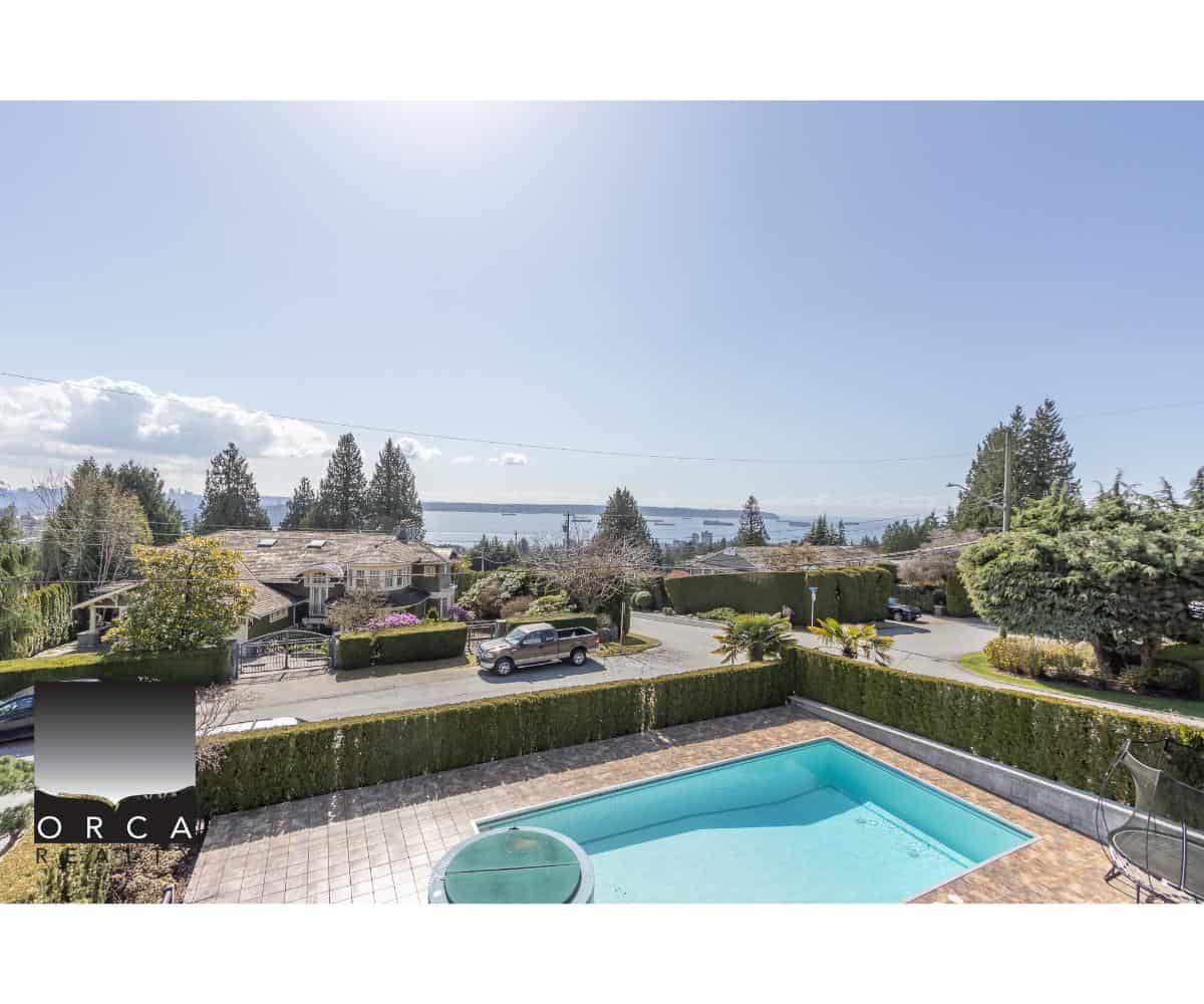 Serene residential neighbourhood with a view of the water, featuring a backyard with a swimming pool, lush landscaping, and well-maintained homes, ideal for Vancouver real estate buyers.
