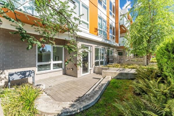 Spacious outdoor patio area in a contemporary Vancouver apartment at 101-7878 Granville Street, showcasing natural surroundings and modern architecture.