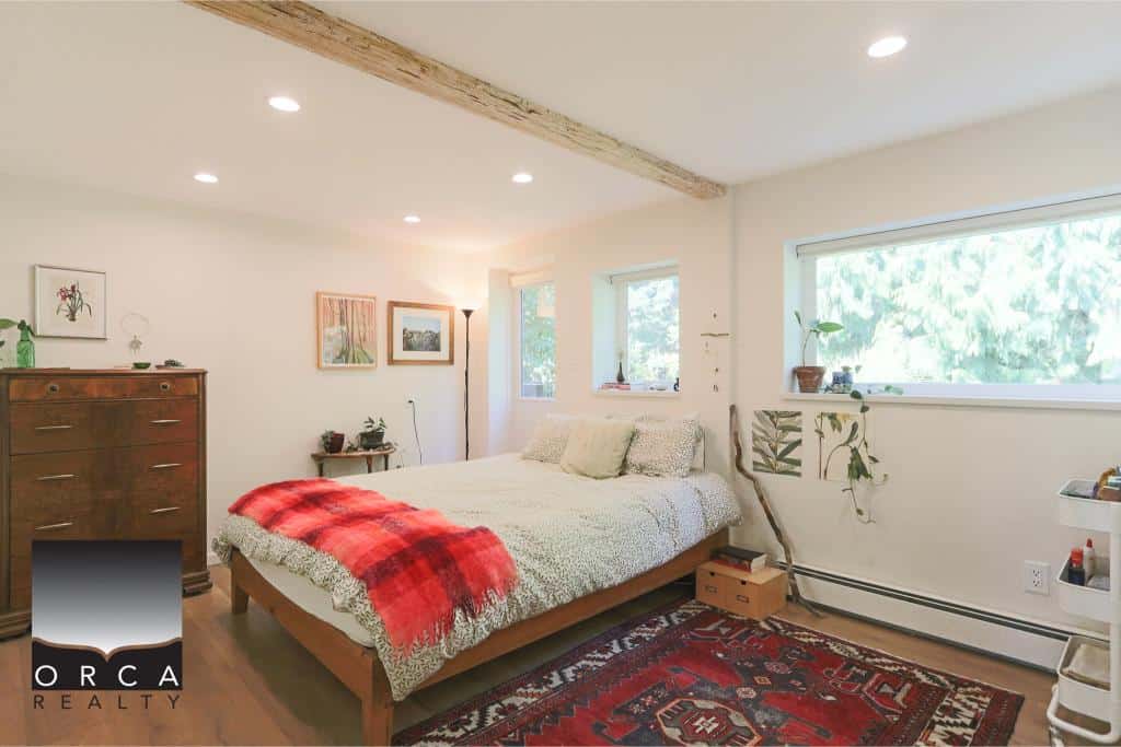 Cozy modern bedroom with natural light, minimalist decor, and rustic accents, ideal for Vancouver Island real estate listings; perfect for buyers seeking comfortable downtown homes.