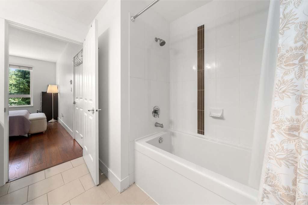 Bright bathroom with white tiles, bathtub, and showerhead featuring modern fixtures in a home listed by Orca Realty Inc.