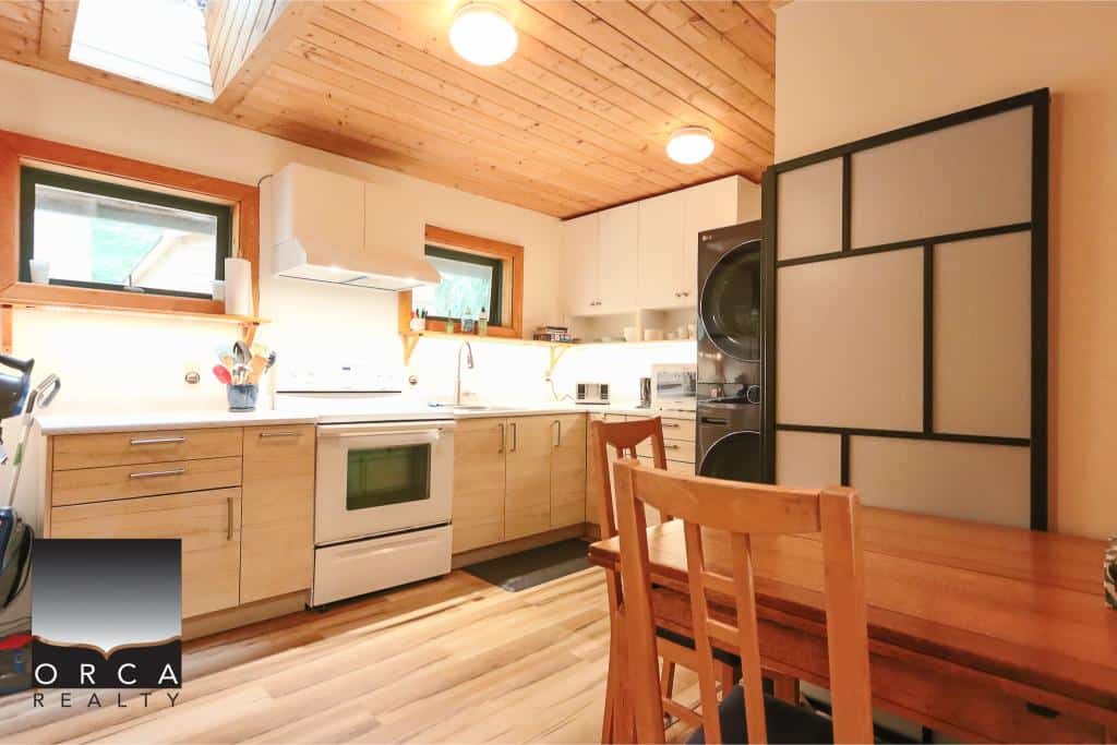 Bright modern kitchen with natural wood cabinetry, skylight, and cozy dining area, ideal for homebuyers seeking a warm and functional space in BC real estate.