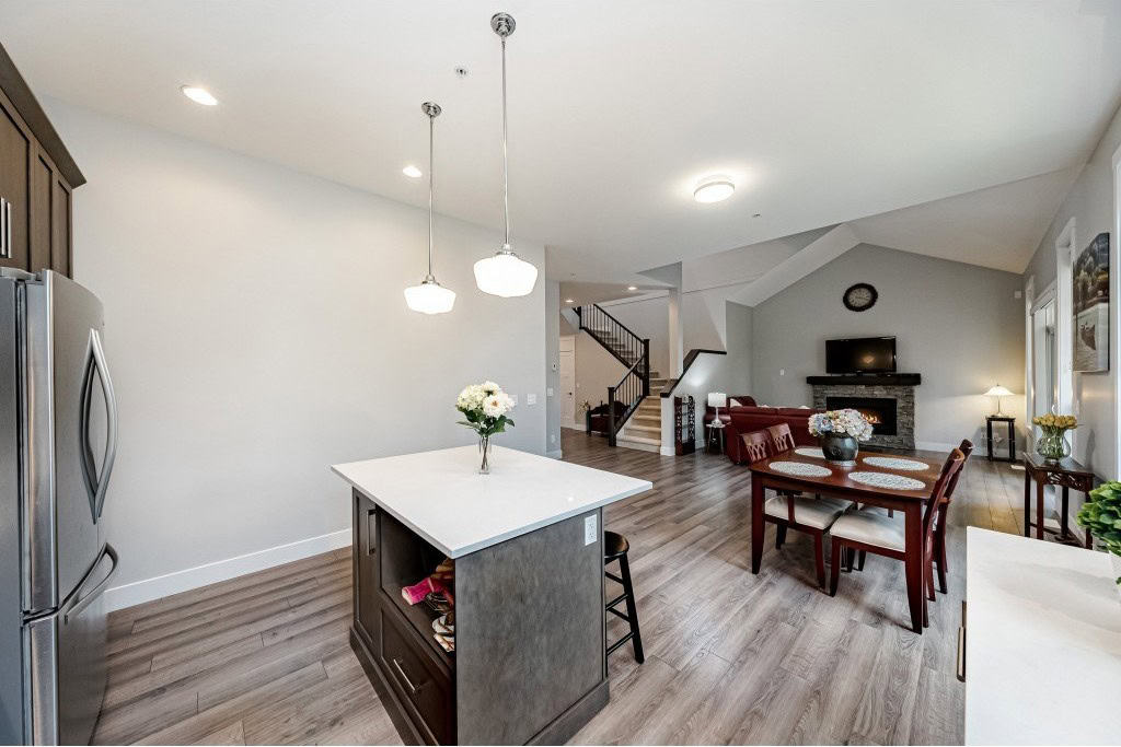 Modern open-concept kitchen and living room interior in a family home, featuring contemporary furniture, hardwood flooring, and a cozy fireplace, perfect for Vancouver area real estate listings.