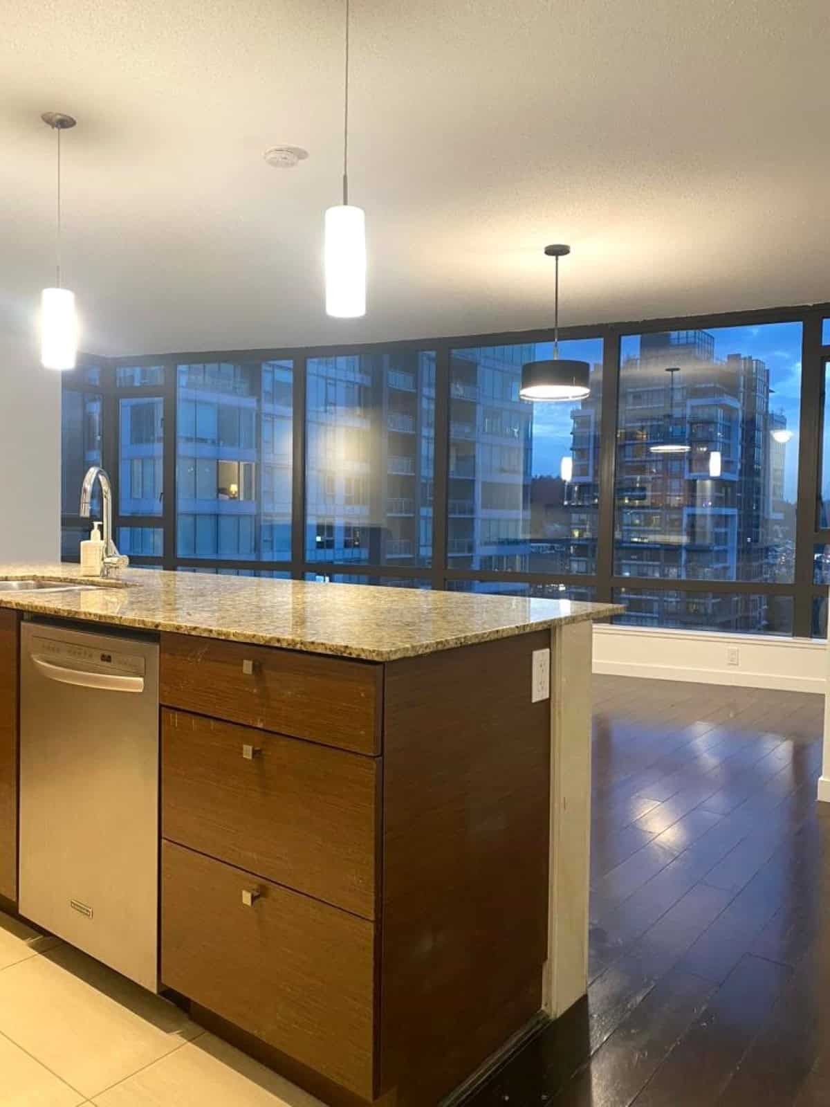 Modern urban condo interior with open kitchen and large floor-to-ceiling windows overlooking city high-rises, ideal for Toronto real estate investments.