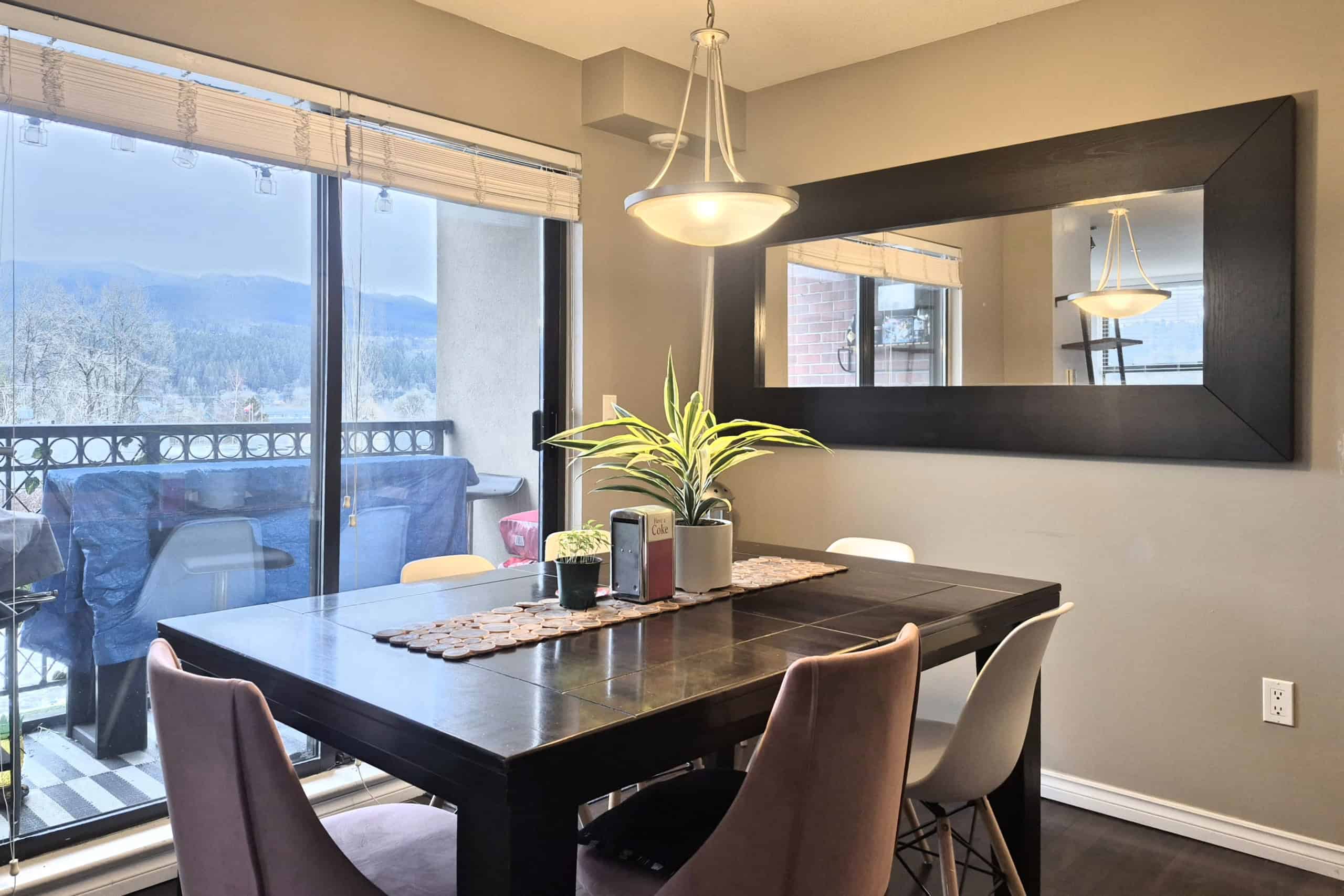Modern dining room with large sliding glass doors showcasing mountain views, featuring a dark wood dining table, stylish chairs, and contemporary lighting, ideal for Vancouver real estate buyers.