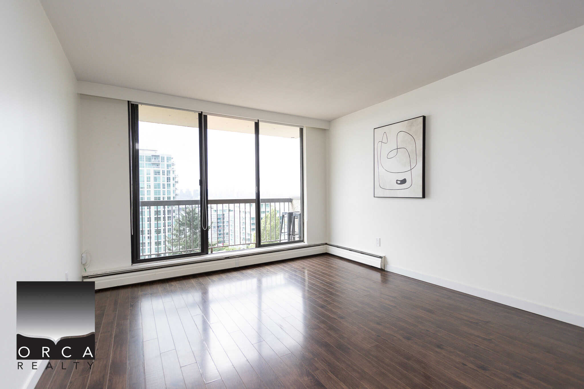 Bright, modern apartment living room with large sliding glass doors leading to balcony, featuring hardwood floors and minimal decor, ideal for Vancouver real estate.