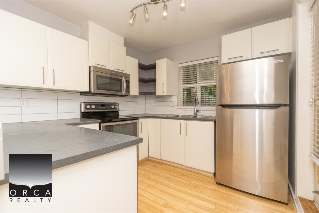 Bright and modern kitchen with stainless steel appliances, white cabinetry, and hardwood flooring, ideal for Vancouver area real estate listings.