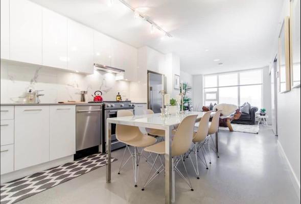 Contemporary Vancouver apartment interior with modern kitchen and open-concept living and dining area, featuring sleek white cabinets, stylish furniture, and abundant natural light.