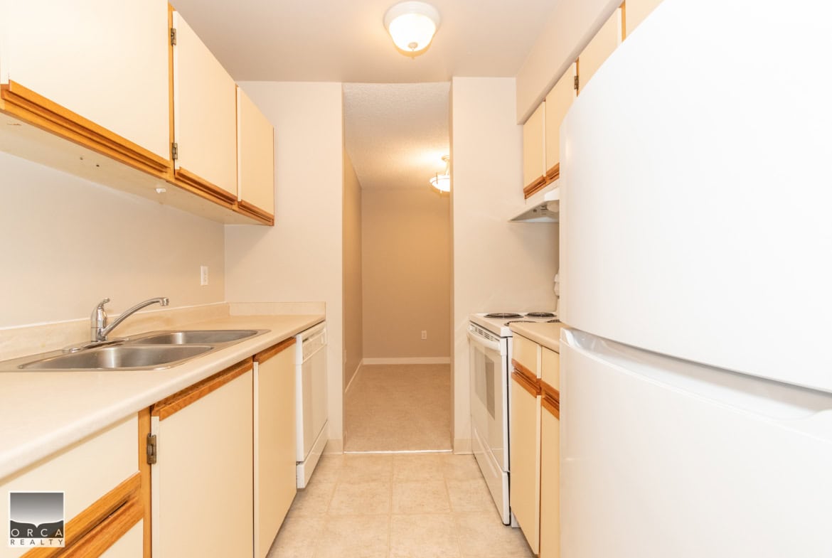 Bright compact kitchen with beige cabinetry, white appliances, and tiled flooring, ideal for small homes or apartments in Vancouver, BC. Perfect for modern living and convenient urban lifestyles.