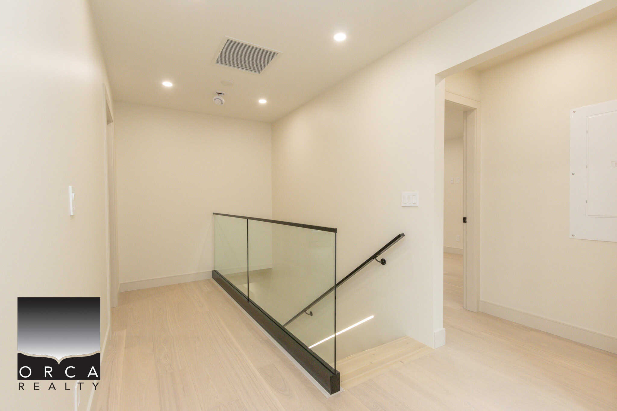 Bright modern interior of a new residential property in Vancouver, featuring sleek staircase with glass railing and minimalist design by Orca Realty Inc., your local Vancouver real estate experts.