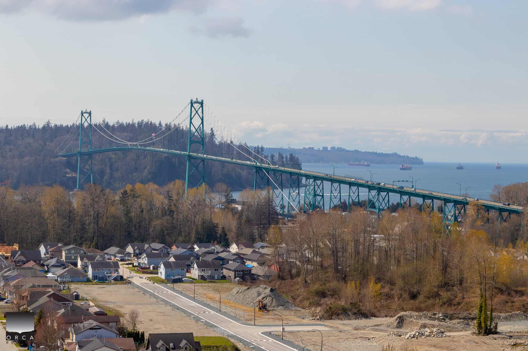 Modern bridge over water with residential houses and forested hills in the background, showcasing scenic Vancouver Island landscape in British Columbia.