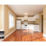 Modern kitchen with white cabinets, refrigerator, stove, and hardwood floors in a cozy home. Bright, inviting space perfect for family living or entertaining guests.