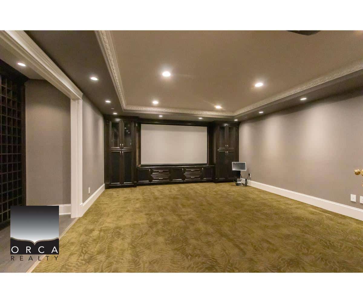Luxury home theatre room with custom dark wood cabinetry, plush beige carpet, and modern recessed lighting, perfect for entertaining in your Vancouver area property – Orca Realty Inc.